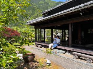 dos personas sentadas en el porche de un edificio en Yado Nishimura Timeless Japan Experience, en Shizuoka