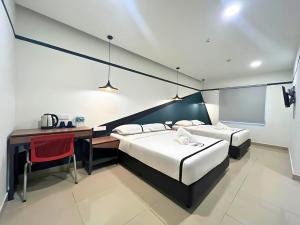 a hotel room with two beds and a desk and a table at Smile Hotel Titiwangsa Pekeliling Sentul in Kuala Lumpur