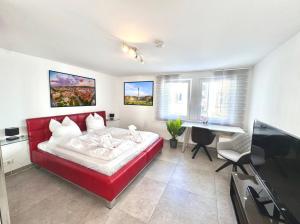 a bedroom with a red bed and a desk at Komfort Oase mit Klimaanlage, Terrasse und Whirlpool in Stuttgart