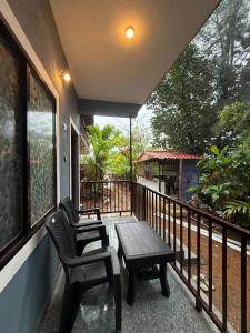 a porch with a table and a bench on a balcony at Omisha Beach Stay Gokarna in Gokarna