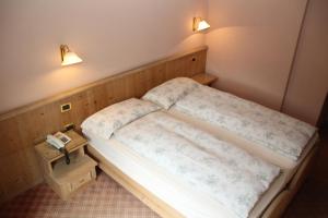 a small bedroom with a bed and a phone at Albergo Caravasc in Livigno