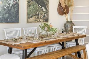 a dining room table with plates and glasses and a vase at Tropical Oasis - Creekside Townhouse by uHoliday in Pottsville