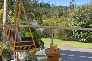 a swinging chair on a porch with a drink at Tropical Oasis - Creekside Townhouse by uHoliday in Pottsville