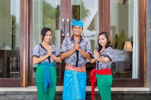 a man and two women standing in front of a building praying at Pondok Baruna Garden in Nusa Lembongan +92 photos