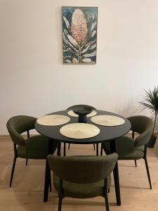 a black table with green chairs and a picture on the wall at Urban Vibe by Atlas Apartment in Prešov