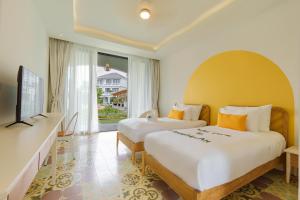 a hotel room with two beds and a television at Moodhoian Riverside Resort & Spa in Hoi An