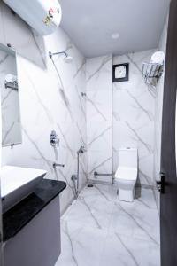 a white bathroom with a sink and a toilet at Hotel Asilo Prime in Indore