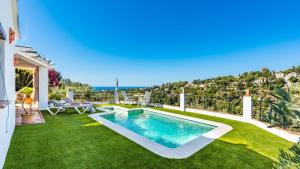 a backyard with a swimming pool and green grass at Casa El Torin Frigiliana by Ruralidays in Frigiliana