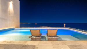 two chairs sitting next to a swimming pool at night at Goseong Moneblue Pension in Goseong