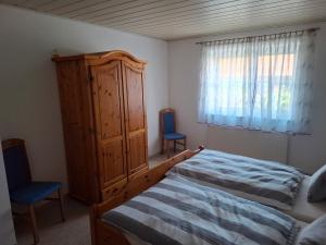 a bedroom with a bed and a wooden cabinet and two chairs at Ferienwohnung Schönhals in Hochwaldhausen