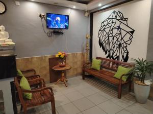 a living room with two benches and a tv on the wall at Hotel EESTEE in Colombo