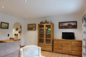 a living room with a television and a wooden cabinet at Haus am See - Wohnung Königssee in Königssee