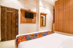 a bedroom with a bed and a flat screen tv at FabHotel Marina in Tangra