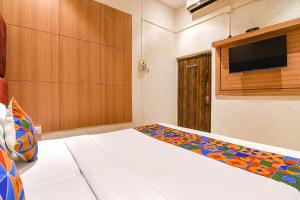 a bedroom with a bed and a tv on a wall at FabHotel Marina in Tangra