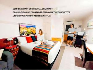 a woman sitting on a bed in a hotel room at Central Studio Accommodation in Gladstone