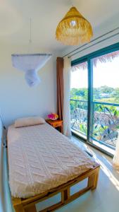 a bedroom with a bed and a large window at belle villa neuve à NOSY BE Ambaro avec 4 chambres in Ambaro