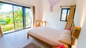 a bedroom with a bed and a large window at belle villa neuve à NOSY BE Ambaro avec 4 chambres in Ambaro