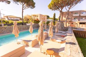 a pool with umbrellas and lounge chairs next to a swimming pool at Hôtel La Ménado in Cavalaire-sur-Mer
