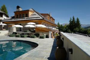 a house with a swimming pool next to a building at Hôtel Le Prieuré - Pra Loup 1500 in Pra-Loup
