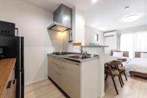 a kitchen with a sink and a table with a bed at Anecis Honjin in Nagoya
