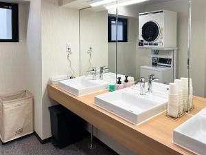 a bathroom with two sinks and a mirror at HOTEL WINDS ASAKUSA Capsule Inn 浅草 in Tokyo
