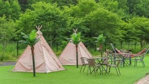 a group of tables and chairs with tents and palm trees at Anmyeondo Town 1967 Dog Pool Villa in Taean