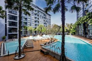 a swimming pool with palm trees and buildings at City gate apartment in Ban Nong Chaeng