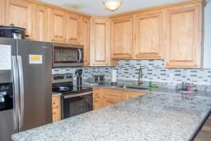 a kitchen with wooden cabinets and a stainless steel refrigerator at Winterplace Ski In Ski Out First Floor D104 in Ghent