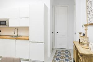 a kitchen with white cabinets and a wooden table at NOMADIA en Plaza de la Constitucion 1 in Málaga
