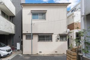 a white building with windows on a street at 日本の生活を体験できる古民家 一棟貸切最大7名 jr上中里駅 in Tokyo