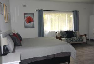 a bedroom with a bed and a chair and a window at Nirvana Cottage in Cape Town