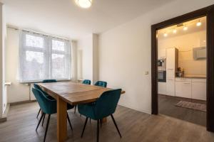a dining room with a wooden table and blue chairs at Theater Apartment in Gera