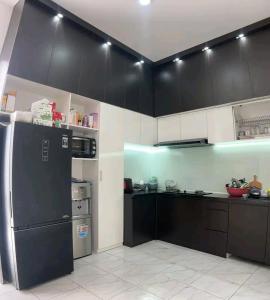 a kitchen with black cabinets and a black refrigerator at Dans House Villa in Brujul