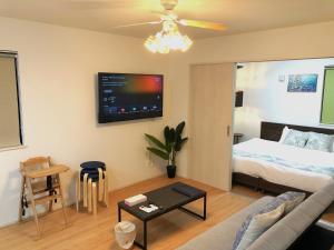 a living room with a bed and a tv on the wall at NIRAI Yofuke in Nago