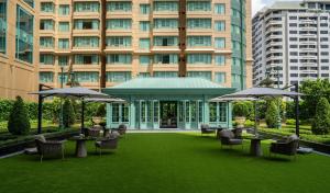 a hotel yard with chairs and tables and umbrellas at Grande Centre Point Prestige Bangkok in Bangkok +77 photos