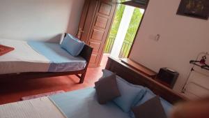 a bedroom with a bed and a window and a door at Wilpattu Gagana guest in Nochchiyagama