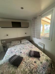 a bedroom with a bed with two pillows on it at Bungalow 87, 8 personnes Camping Siblu Le Lac des Reves in Lattes