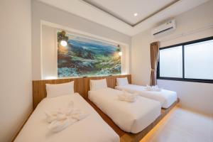 a bedroom with two beds and a painting on the wall at White berry pool villa aonang in Krabi town