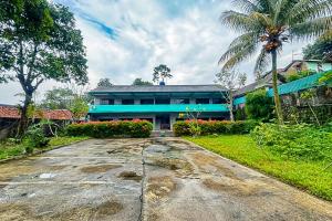 a building with a palm tree in front of a road at Garden View near Batu Tulis RedPartner in Bogor +13 photos