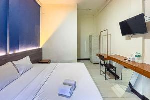 a bedroom with a bed and a desk and a television at Garden View near Batu Tulis RedPartner in Bogor