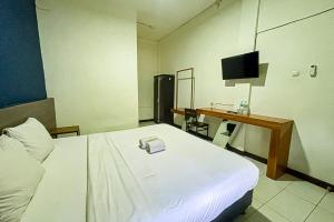 a bedroom with a bed and a desk with a television at Garden View near Batu Tulis RedPartner in Bogor
