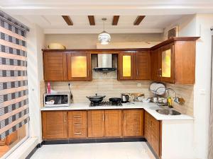 a kitchen with wooden cabinets and a sink and a microwave at Luxury Apartment Guest House in Islamabad +38 photos