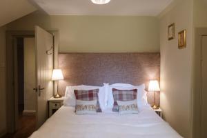 a bedroom with a white bed with two pillows at The Coach House in Castle Douglas
