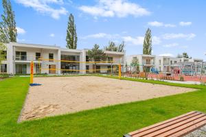 a volleyball court in front of a building with a playground at GRANO FLATS - Sobieszewo - Pino Resort in Gdańsk
