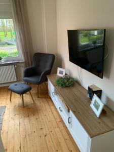 a living room with a television and a chair at Huus an't Zingel - Ferienhaus in Krummhörn-Rysum in Rysum