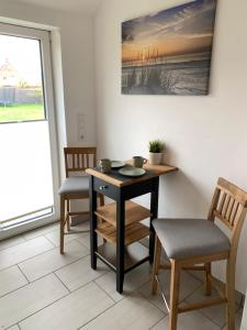 a room with a table and two chairs and a painting at Huus an't Zingel - Ferienhaus in Krummhörn-Rysum in Rysum