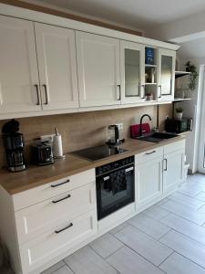 a kitchen with white cabinets and a stove top oven at Huus an't Zingel - Ferienhaus in Krummhörn-Rysum in Rysum +17 photos