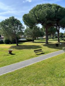 a park with a bench and trees and a path at Appartamenti del Mare in Marina di Bibbona