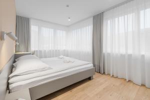 a bedroom with a bed with white sheets and curtains at Prenočišča AUTUR in Tolmin