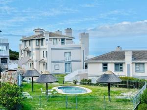 a large white building with a swimming pool and umbrellas at Pinnacle Golf Villa 24-3 in DʼAlmeida